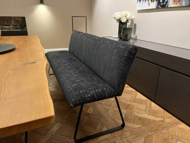 Schwarze Bank, Holztisch, Blumenarrangement.