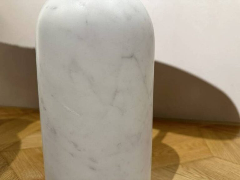 Weiße Marmorflasche auf Holzboden.