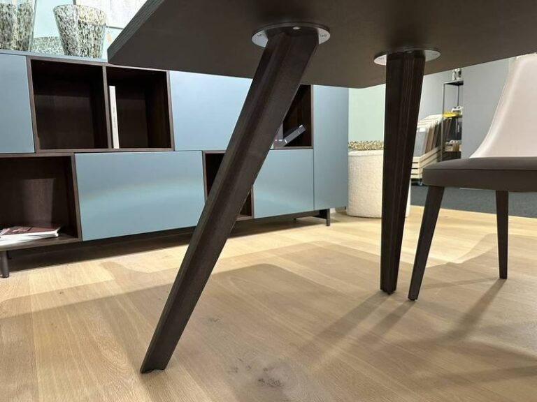 Schräge Tischbeine, blauer Schrank.