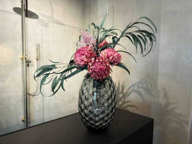 Rosa Blüten in glasiger Vase.