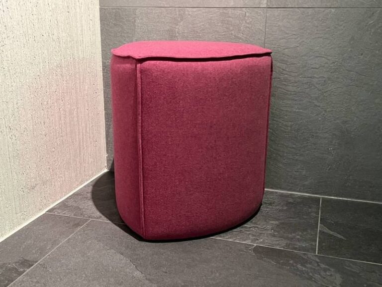 Pinkfarbener Hocker in Ecke.