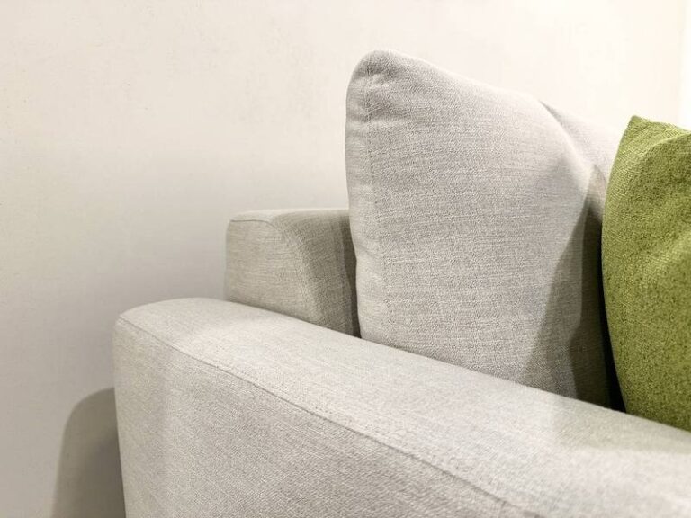 Helles Sofa mit grünes Kissen.