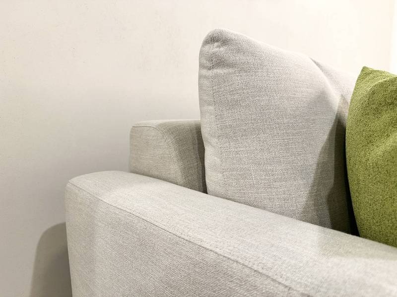 Helles Sofa mit grünes Kissen.