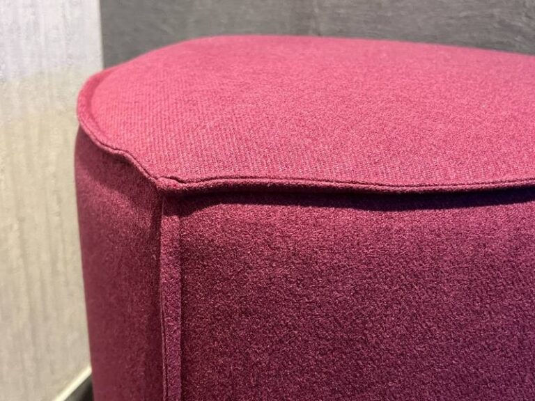 Bordeauxroter Hocker mit Stoffbezug.