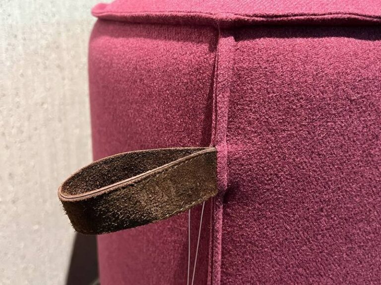Rosafarbener Hocker mit Lederschlaufe.