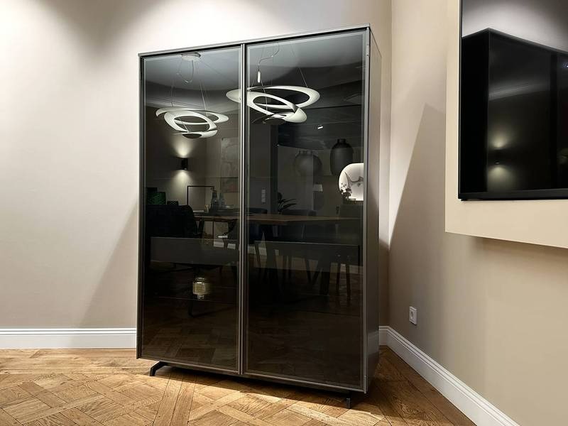 Dunkler Glasschrank mit Lichtreflexion.