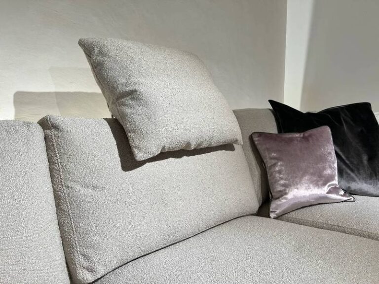 Kissen schwebt über grauem Sofa.