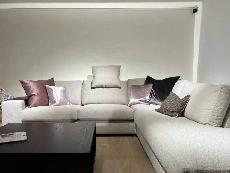 Cremefarbene Couch, glänzende Kissenvielfalt.