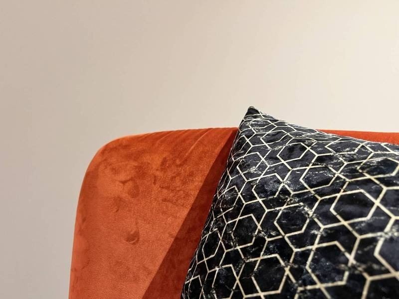 Orange Sessel, geometrisches Kissenmuster.