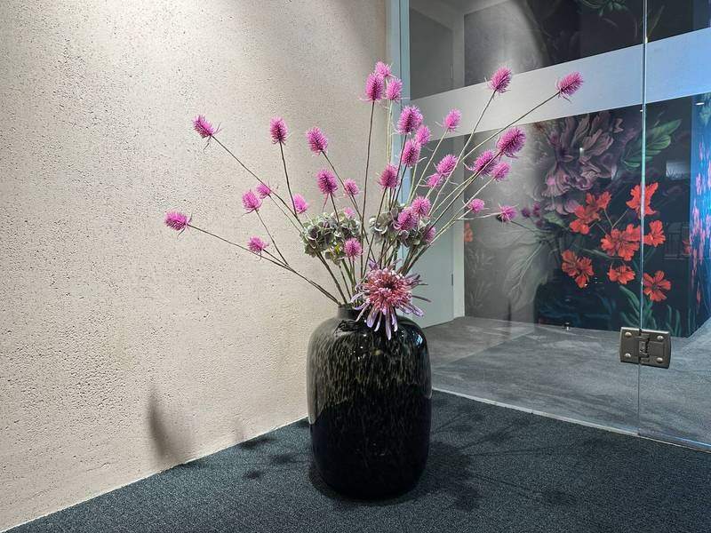 Schwarze Vase, pinke Kunstblumen.